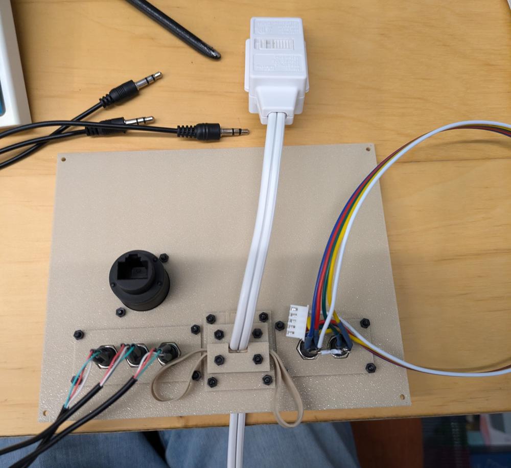 The back side of the above image. There is a small power strip coming through the middle of the plate and wires coming out of the back of each audio port