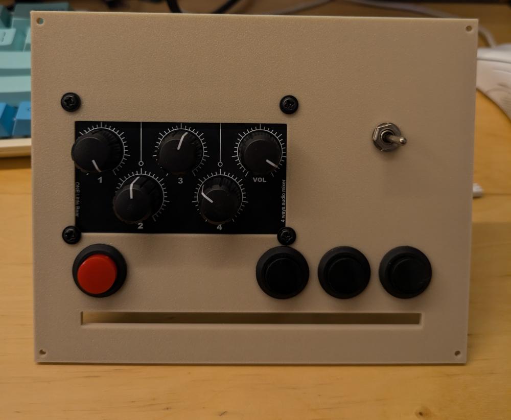 A flat 3d printed panel with screw holes in it's 4 corners. It has 4 buttons, 5 knobs for adjusting volume, and a switch