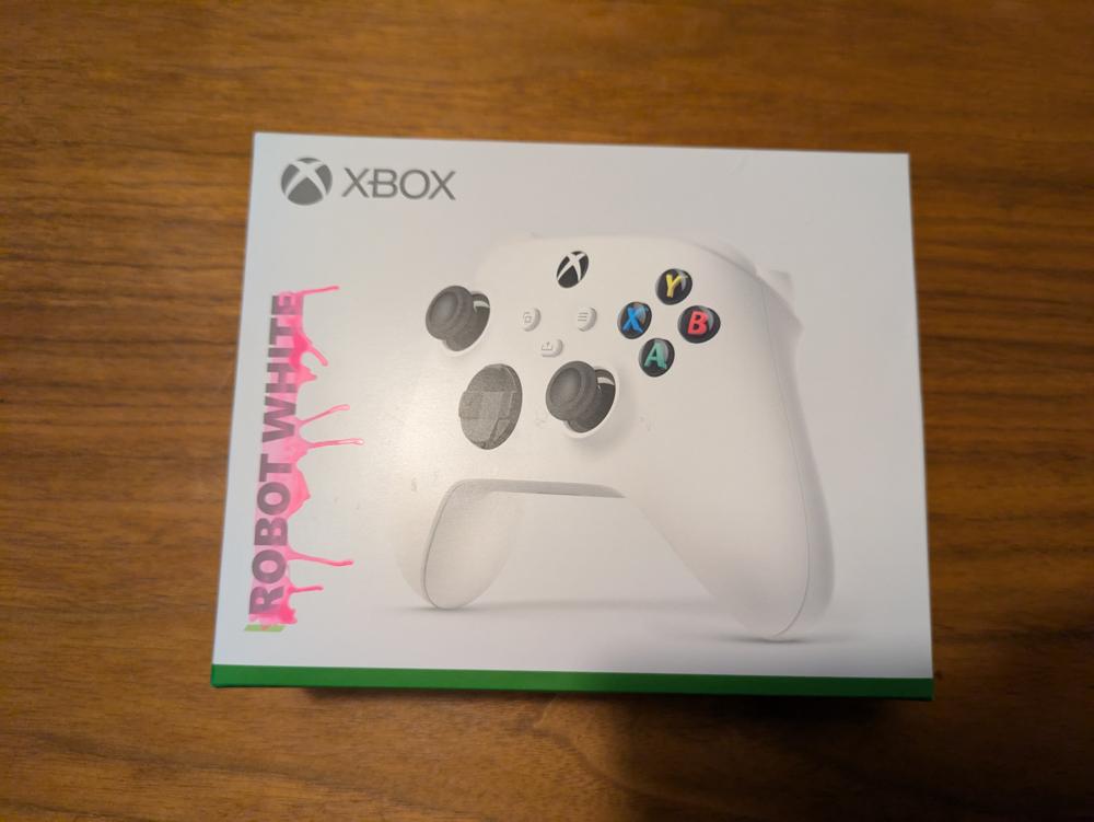 The closed original product box with the text "robot white". The text robot white is covered in a thin layer of pink dripping paint, highlighting the text.