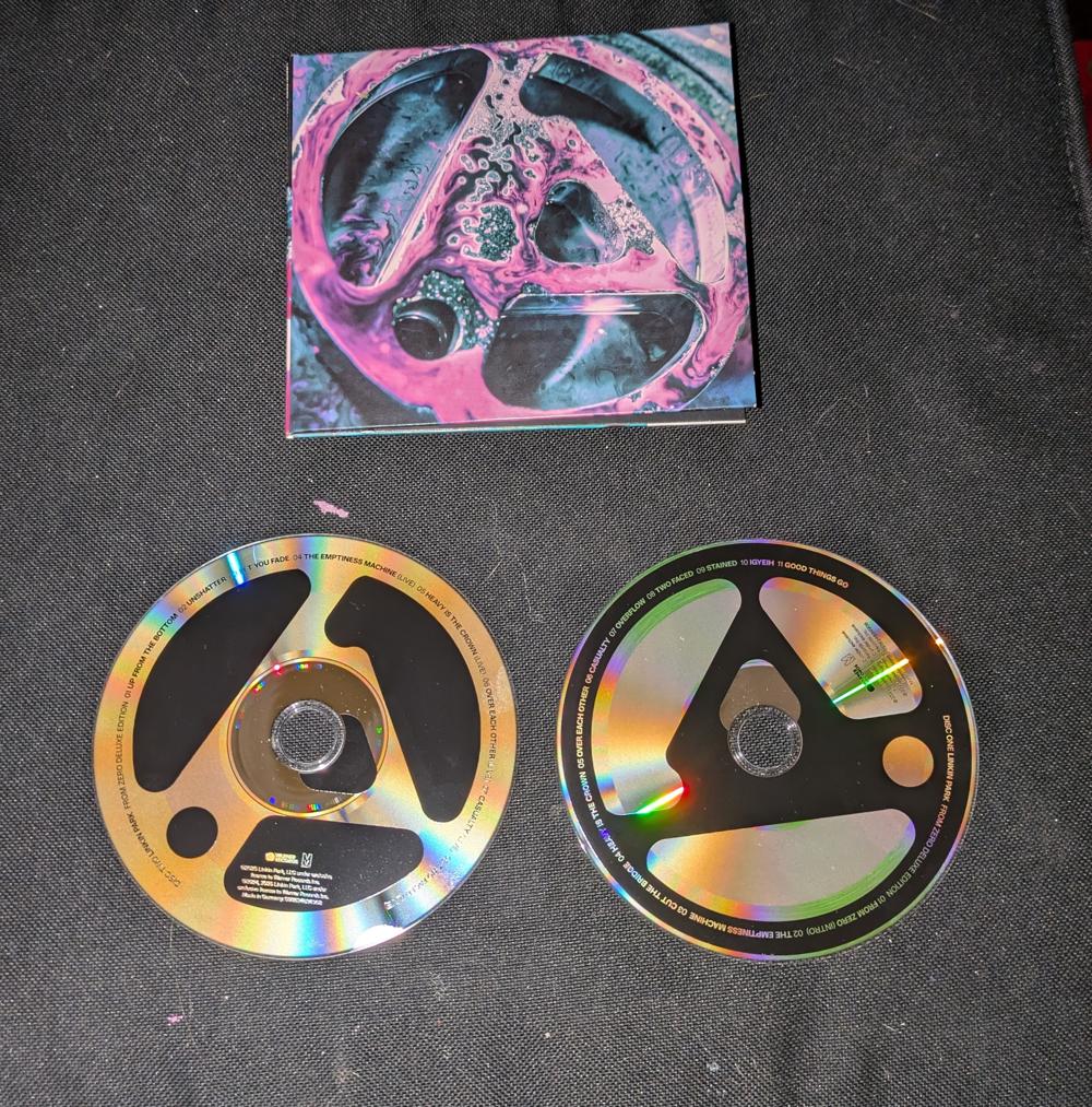 A digipack cd holder and 2 cd's. The 2 cd's have inky black printing against a holographic silver background