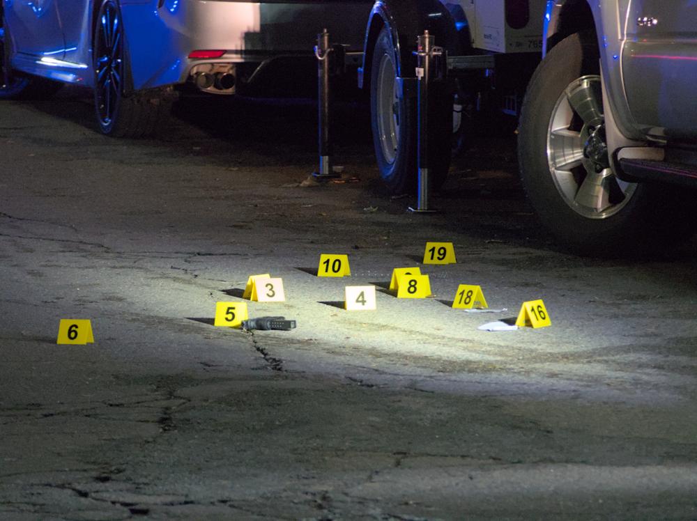 a gun laying on the ground, with bright yellow evidence markers around it