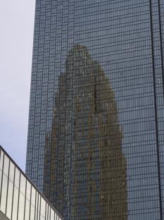 Subway connecting to skyscraper, another skyscraper reflecting off the glass.