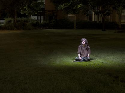 An image of the site's author sitting in a grassy area with a spotlight over them